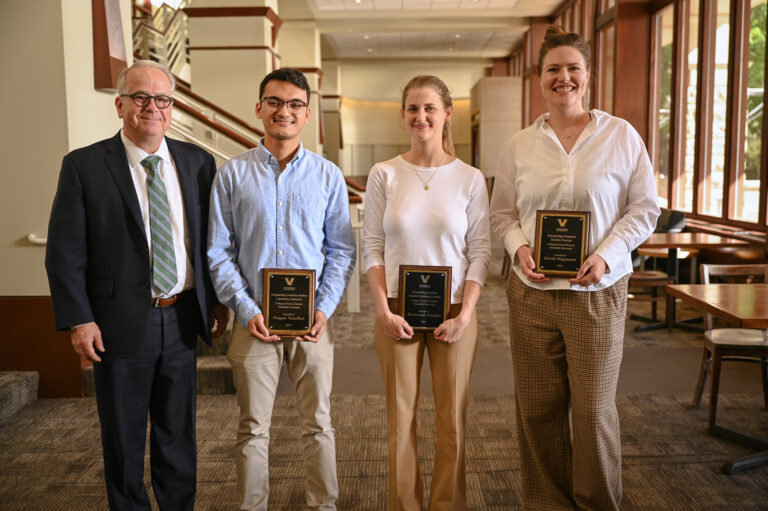 A faculty member with three graduate students and their awards